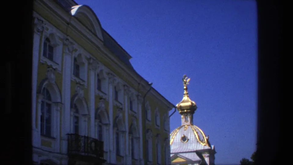 1975 Denmark 8mm frame capturing ornate yellow-and-white architecture, a dark balcony railing, and a bright golden dome.