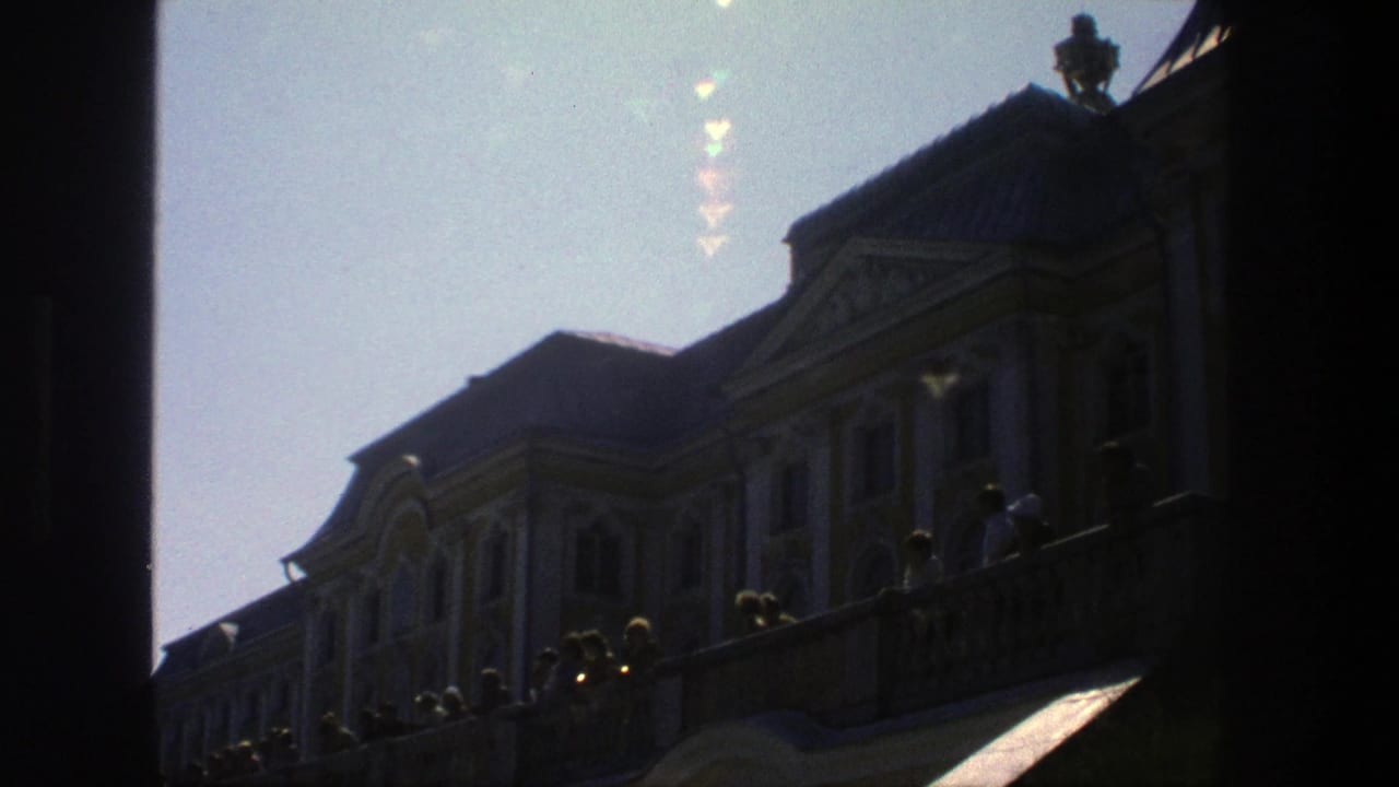 Backlit palace roof and terrace with small visitor figures near the balustrade.