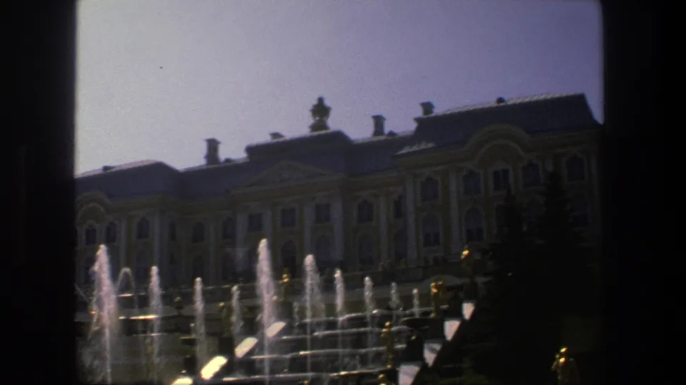 1975 Denmark 8mm frame showing the ornate building, active fountains, clipped evergreens, and a dark edge from the film or camera framing.