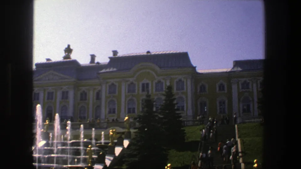 1975 Denmark home-movie frame showing fountains before a classical palace, with visitors visible near the steps.