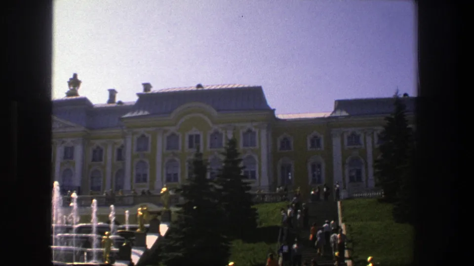 8mm travel footage frame from Denmark in 1975 with visitors on palace steps, fountains, lawns, and a bright sky.