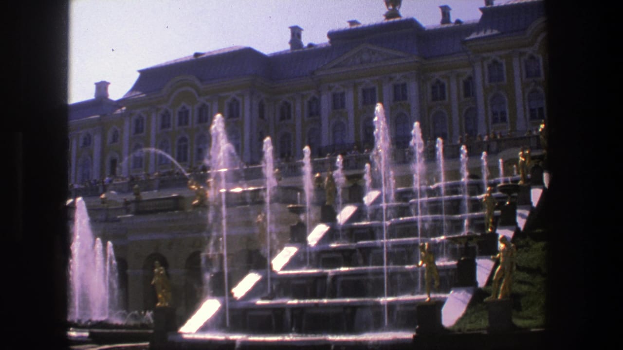 Ornate palace facade behind stepped fountains with gilded statues and water jets.