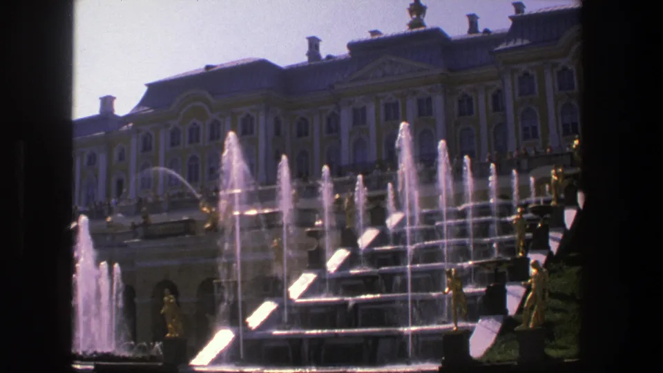 1975 8mm Denmark travel footage frame with cascaded fountain steps, bright water jets, gilded figures, and a palace backdrop.