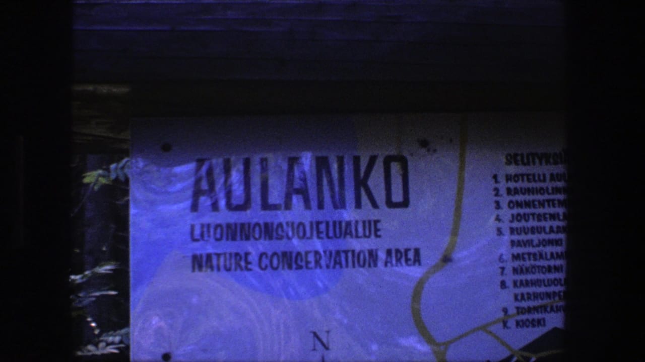 Weathered Aulanko Nature Conservation Area sign seen in blue-tinted low light.