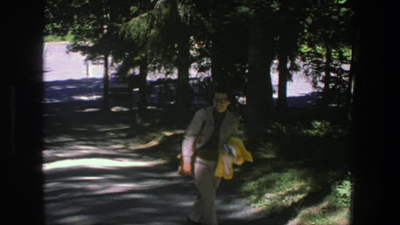 Woman continues walking along the shaded path with trees behind her.
