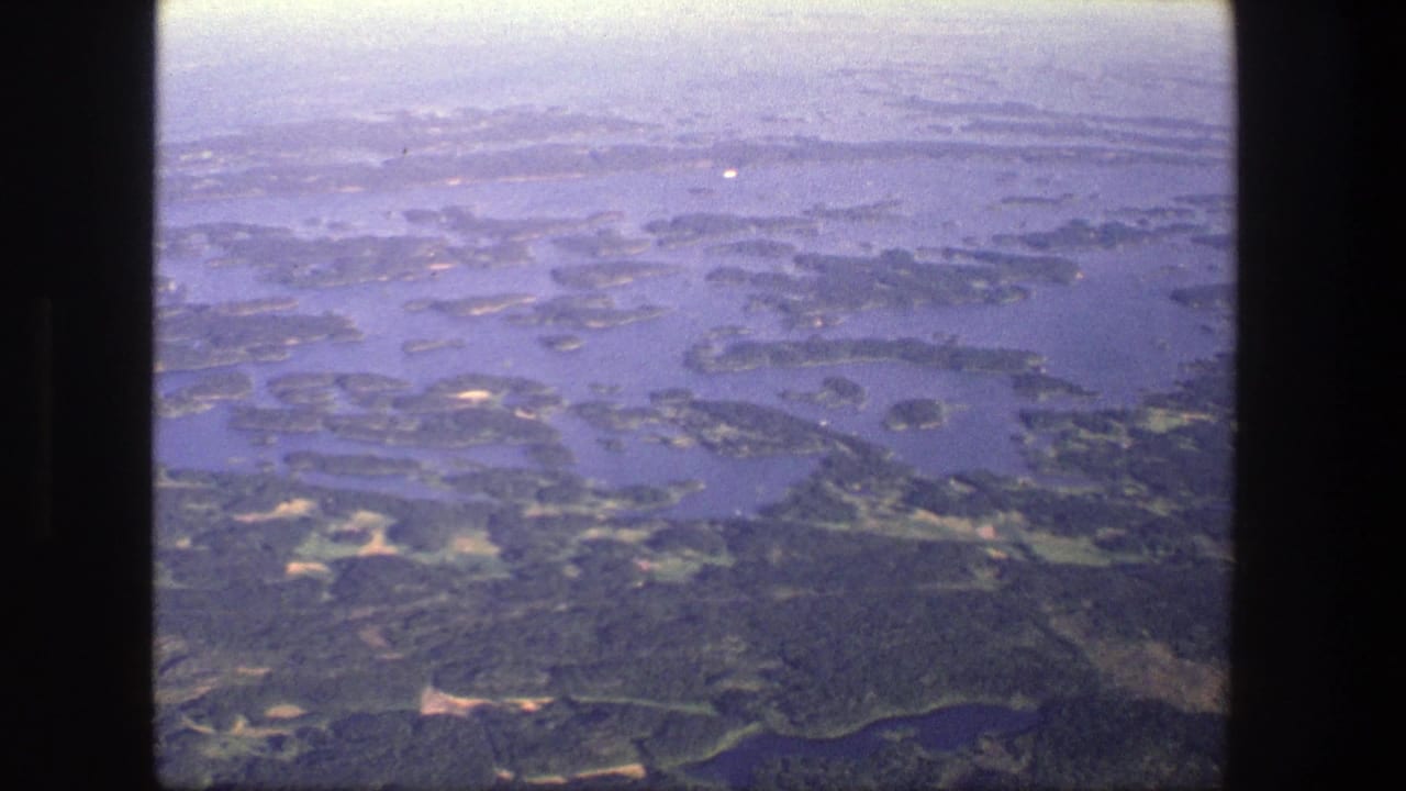 Aerial view of forested islands and blue waterways seen through a film frame.