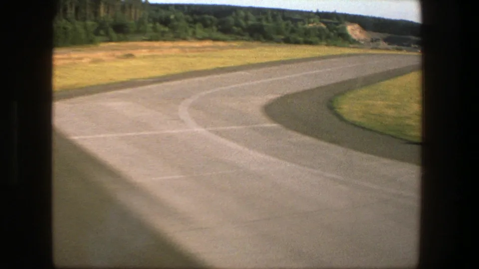 1975 Denmark 8mm view of runway pavement bordered by grass during the final moments of an aircraft descent.