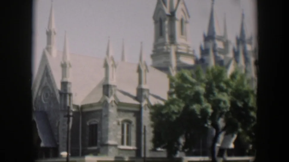 1951 Wyoming 8mm frame showing part of a large Gothic-style church or landmark with pointed spires, pale trim and trees.