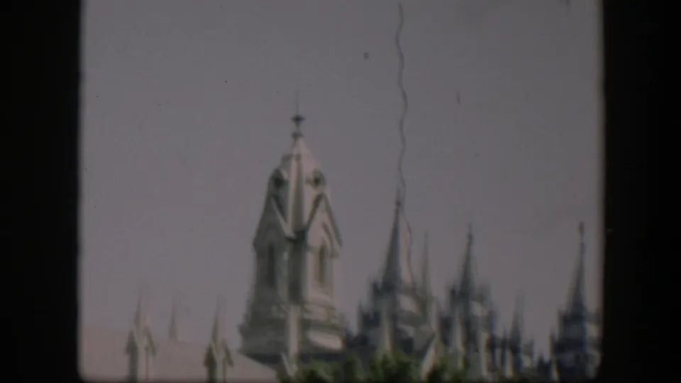 1951 Wyoming 8mm frame with a soft upward view of a church-like turret, spires, roof peaks and faint trees below.