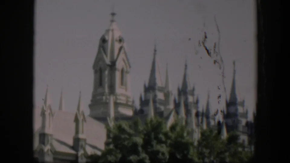 1951 Wyoming 8mm frame showing a pale castle-like landmark with ornate towers rising behind leafy trees.