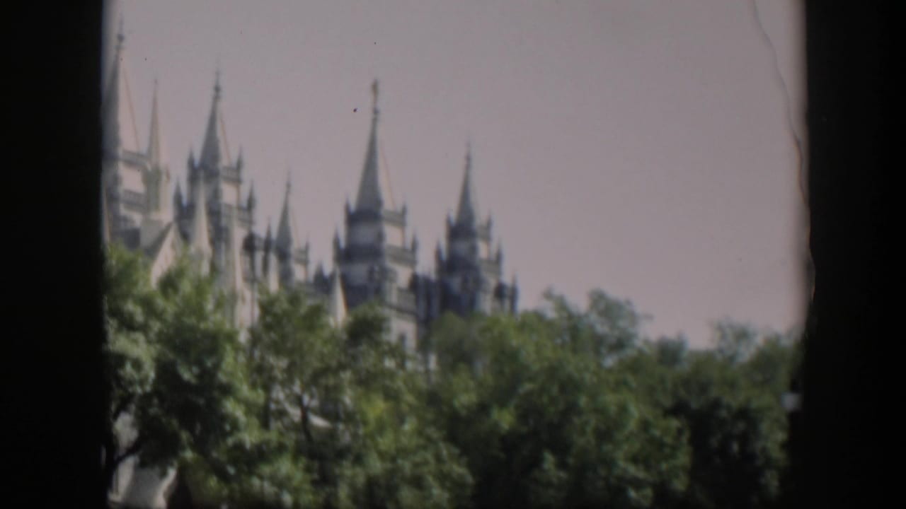 Distant spired temple rising above trees, framed by dark film borders.