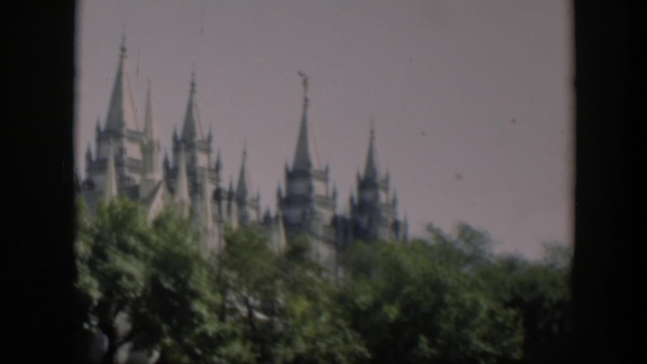 Spired temple partially obscured by trees with dark vertical frame edge.