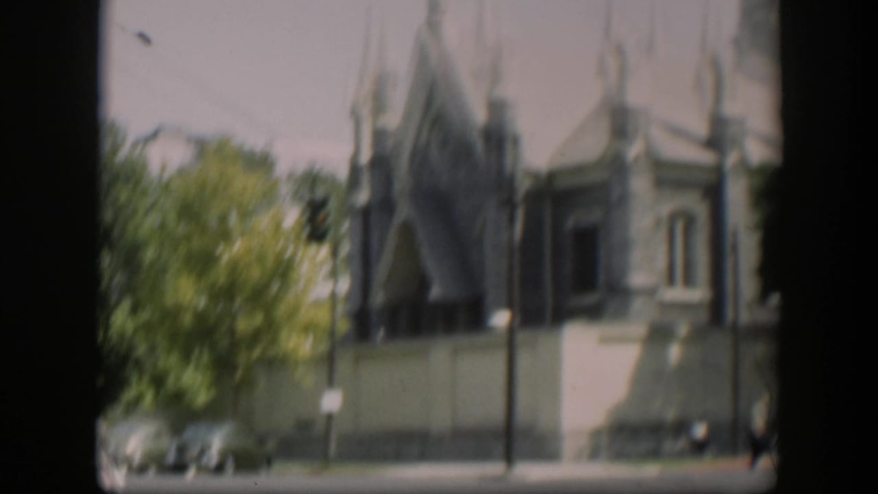 Church wall and spires partly framed by trees and street elements.