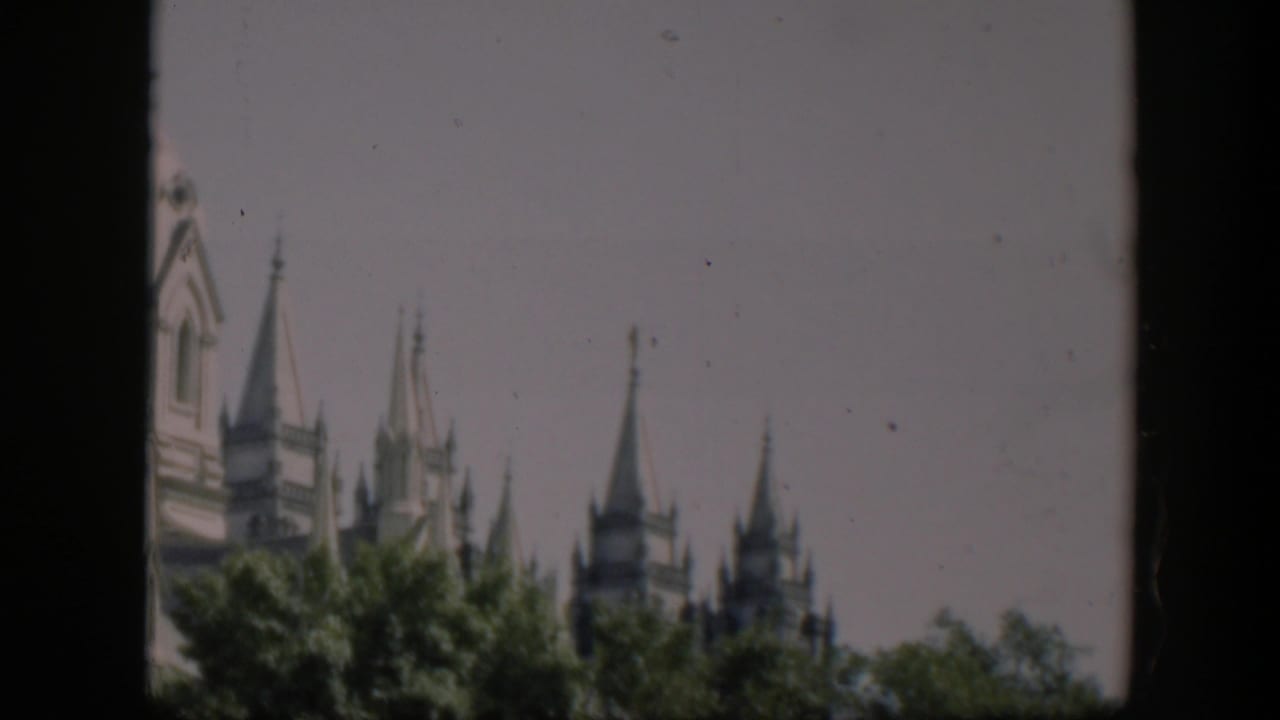 Wyoming 1951 home-movie frame showing pointed spires beyond trees, partly obscured by the edge of the film frame.