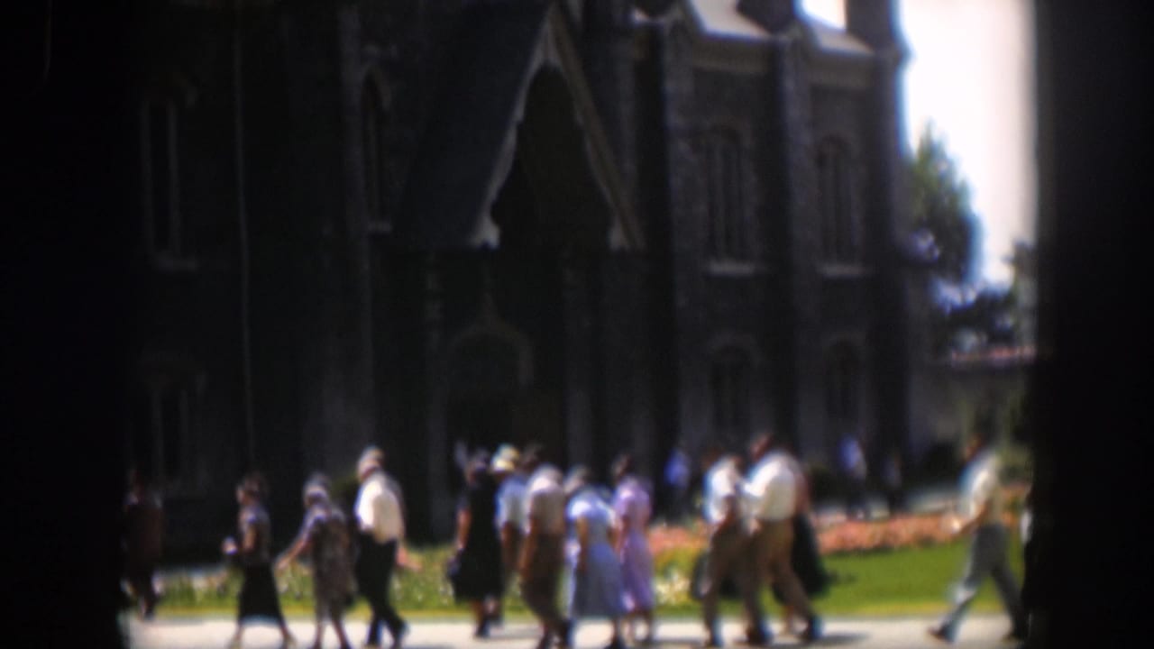 A larger group walks across the church lawn area near the stone facade.
