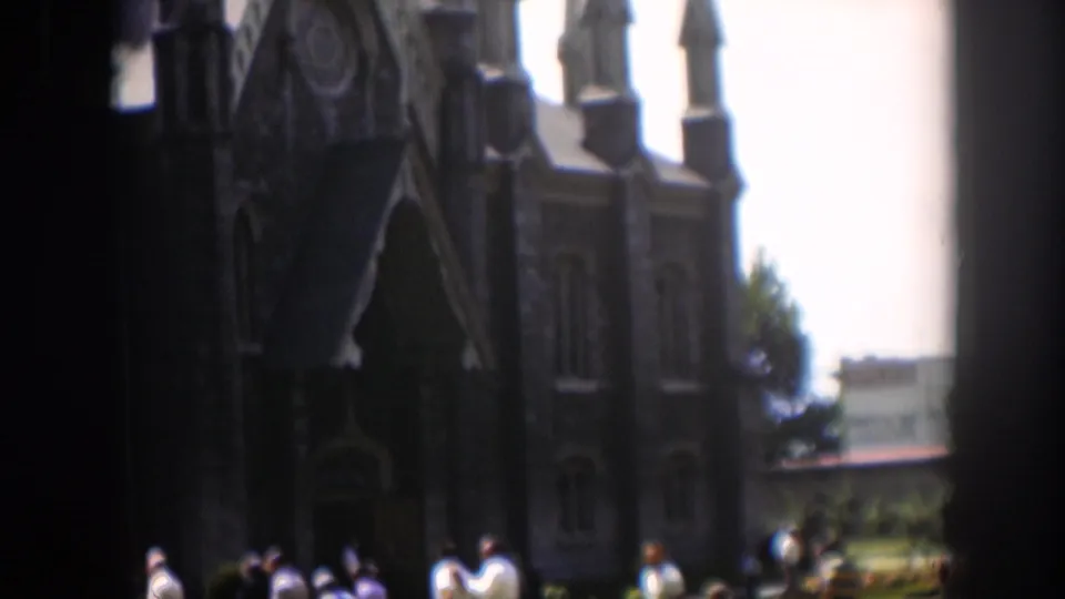 Adults in dress clothes stand and walk near the dark entrance of a large stone church in Wyoming, based on supplied metadata.