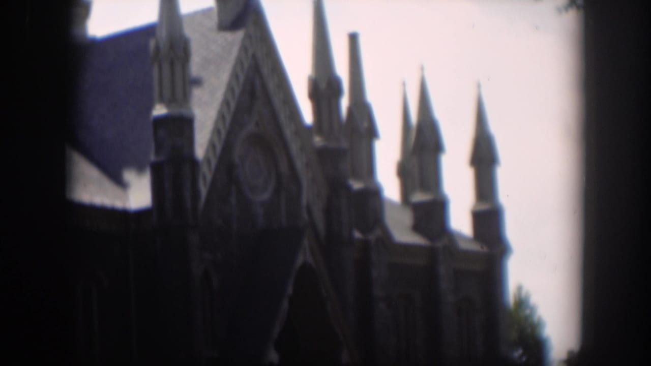 1951 Wyoming 8mm frame showing a Gothic-style church exterior with pointed spires, a steep roof, and a pale sky.