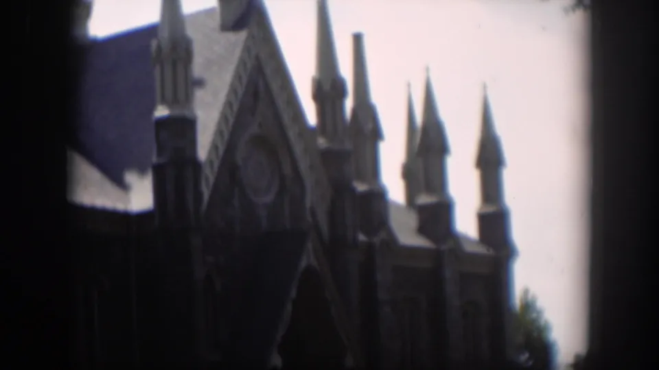 1951 Wyoming 8mm frame showing a Gothic-style church exterior with pointed spires, a steep roof, and a pale sky.