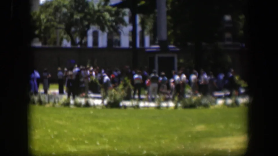 1951 Wyoming 8mm frame showing a distant public gathering near a monument-like feature in a landscaped park.
