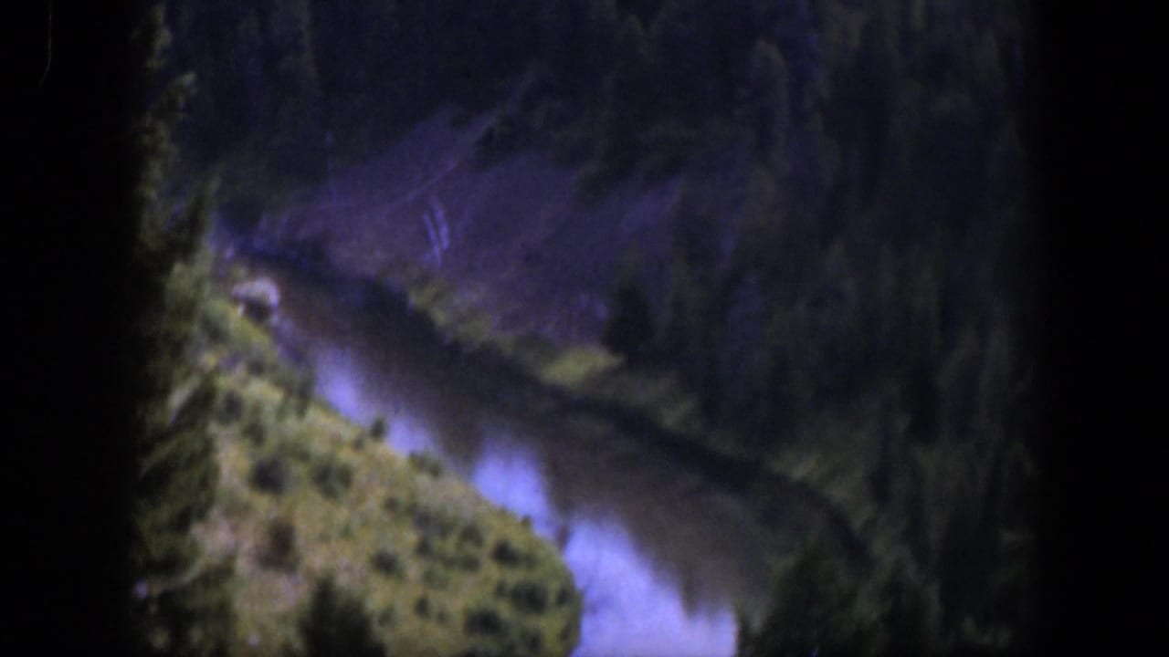 1951 Wyoming 8mm frame showing a mountain river winding below dense pines and a brushy hillside.