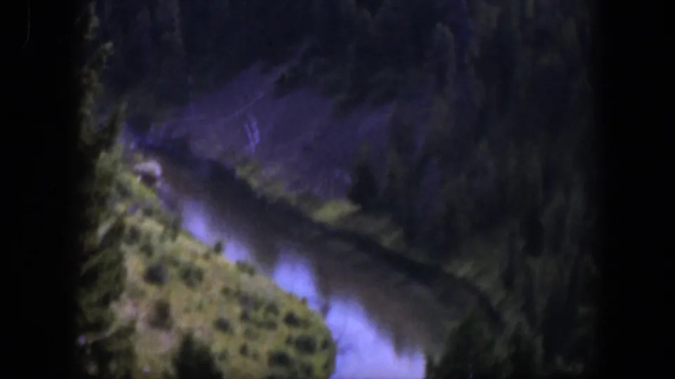 1951 Wyoming 8mm frame showing a mountain river winding below dense pines and a brushy hillside.
