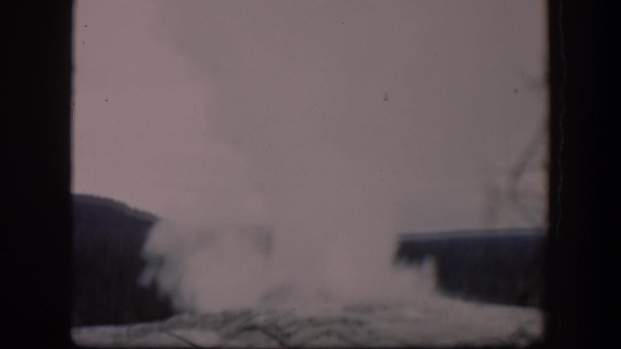 1951 Wyoming 8mm frame showing a pale steam plume from a geothermal vent, partly obscured by film gate bars and soft focus.