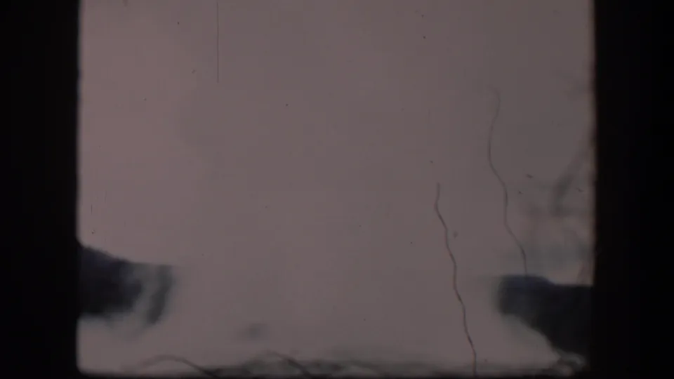 1951 Wyoming 8mm frame where dense geyser steam nearly washes out the view, with vertical scratches and dark film borders visible.