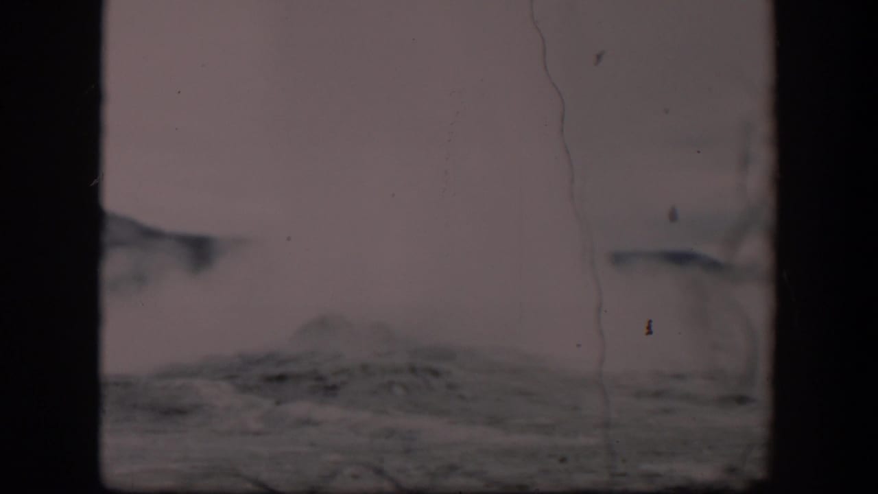 Steam and gray rocky ground under a pale cloudy sky.