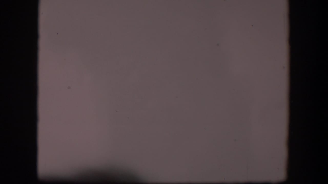 Mostly blank dusty film frame with dark gate edges and faint ground at the bottom.
