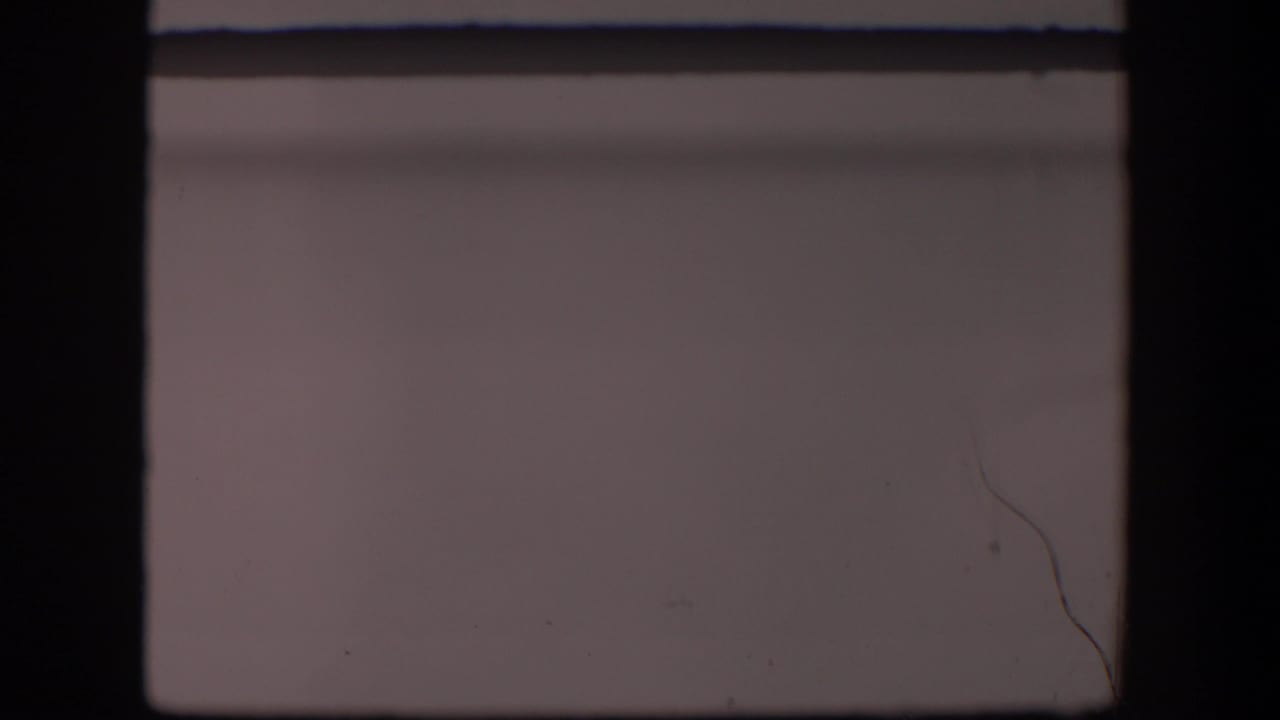 Dark 8mm frame border around a pale, mostly blank landscape view with faint dust and scratches.