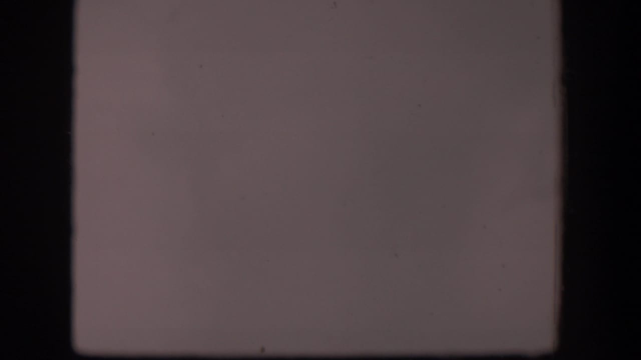 1951 Wyoming 8mm frame showing a washed, nearly featureless view with dark gate borders and visible surface marks from the film scan.