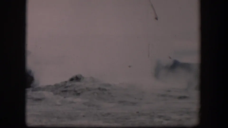 A visitor-shot 1951 8mm frame shows Old Faithful steam dispersing over Yellowstone’s rough geyser basin surface.