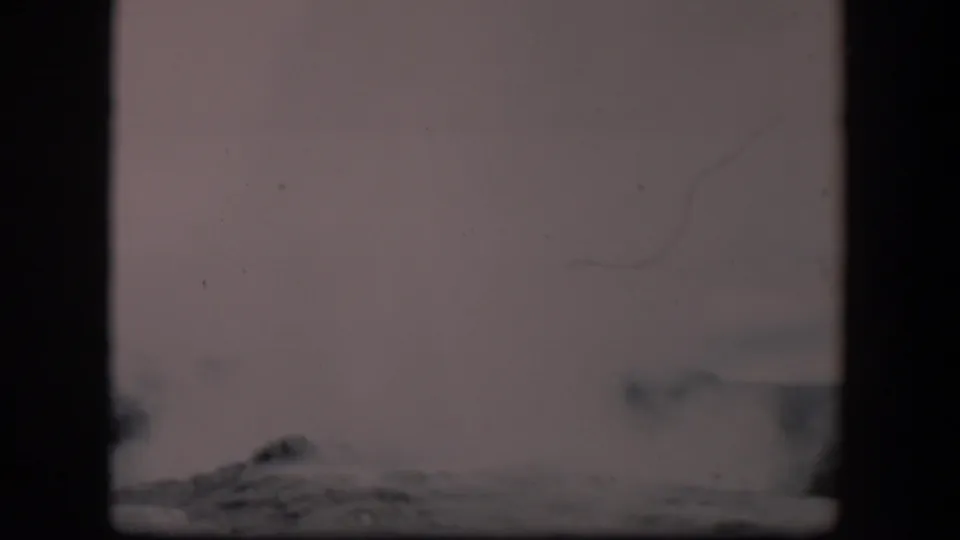 Late in the clip, the Old Faithful plume is partly low in frame, with pale sky, film scratches, and dark frame borders visible.