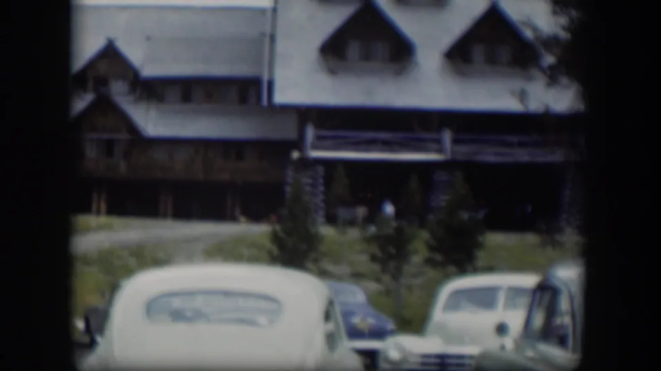 A late shot centers the lodge exterior behind several rounded parked cars in 1951 Wyoming home-movie footage.