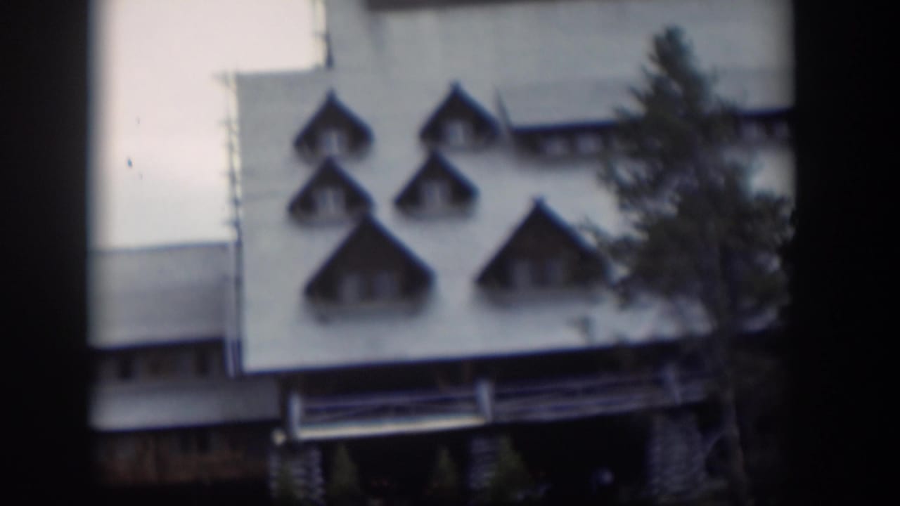 1951 Wyoming home-movie frame of the same white building, with pointed dormer windows and an evergreen partly covering the right side.