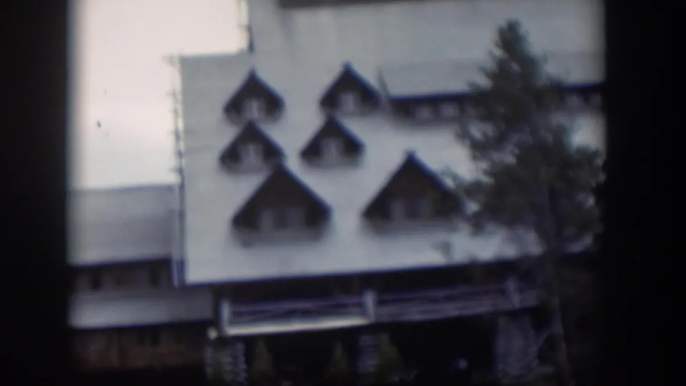 1951 Wyoming home-movie frame of the same white building, with pointed dormer windows and an evergreen partly covering the right side.