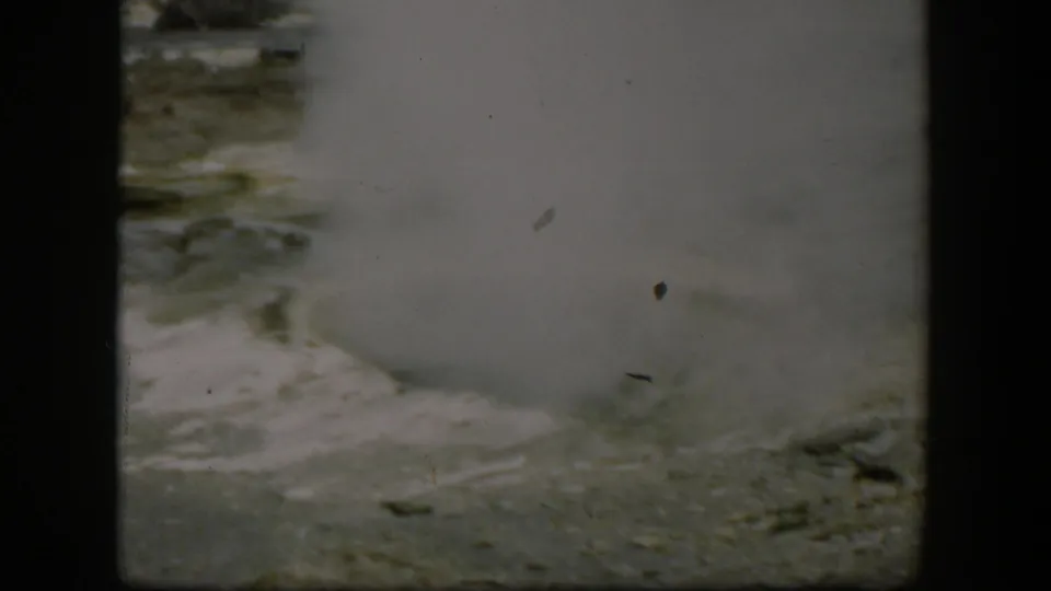 1951 Wyoming 8mm frame showing thick geyser steam over pale mineral ground in Yellowstone National Park.