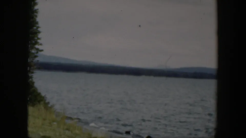 1951 Wyoming lake view with soft focus, dark frame borders, a narrow grassy bank, and low hills under gray sky.