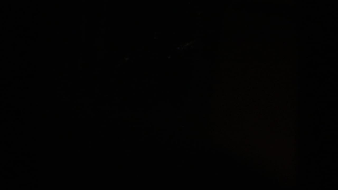 Very dark frame with faint vertical edges and little visible detail.
