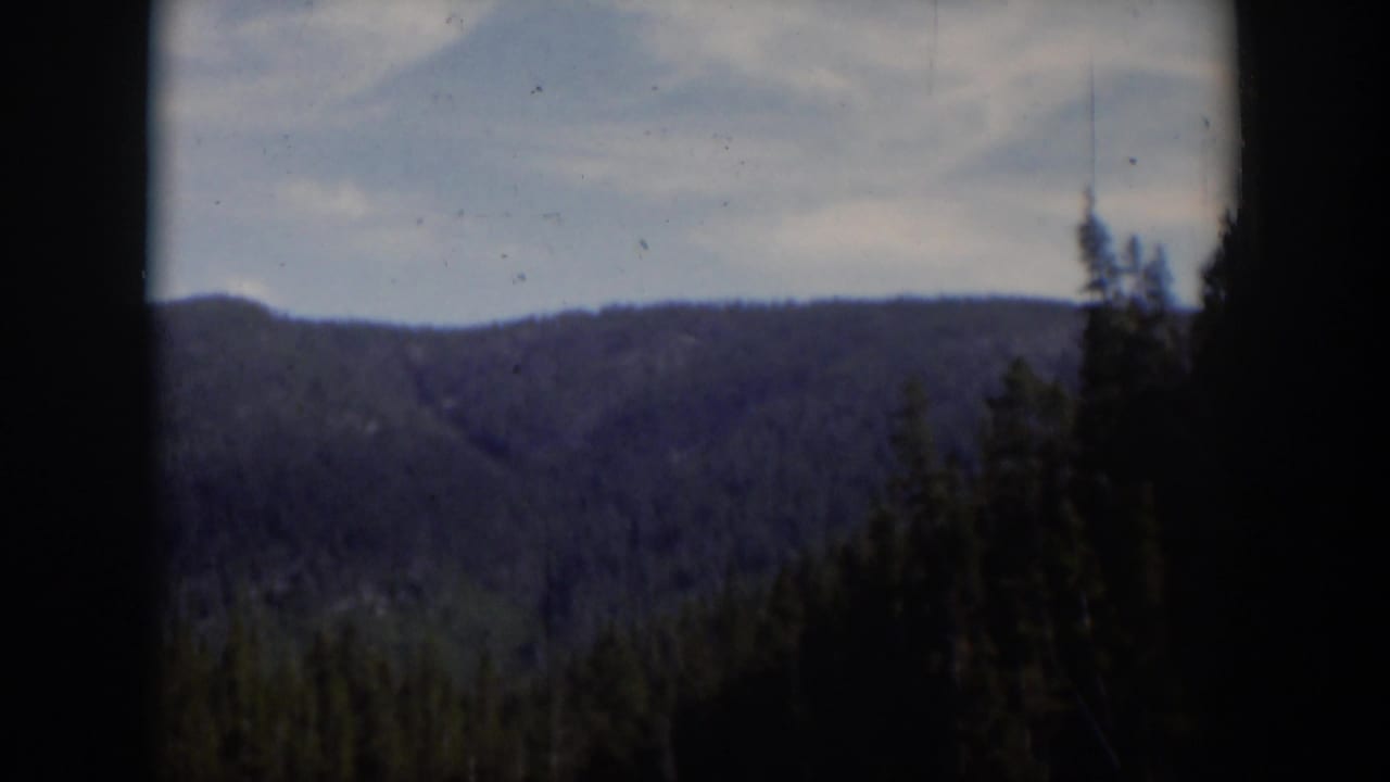 Forested mountain ridge seen through dark 8mm frame borders.
