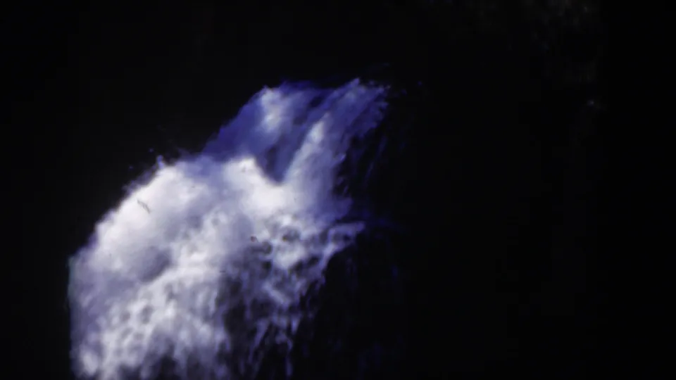 1951 Wyoming 8mm frame focused on churning white waterfall foam against a dark rocky drop, with strong contrast and small-gauge film grain.