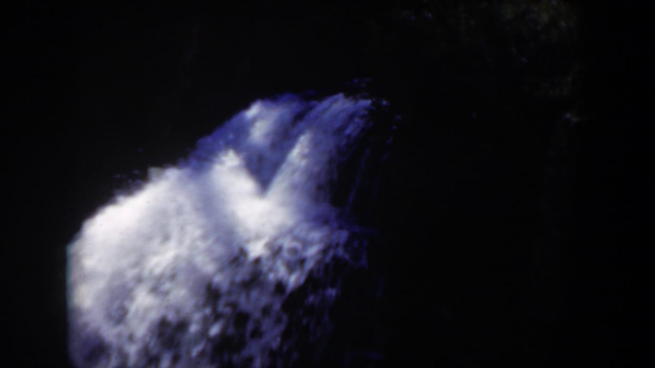 1951 Wyoming 8mm frame showing a bright blue-white waterfall against a nearly black forest background.