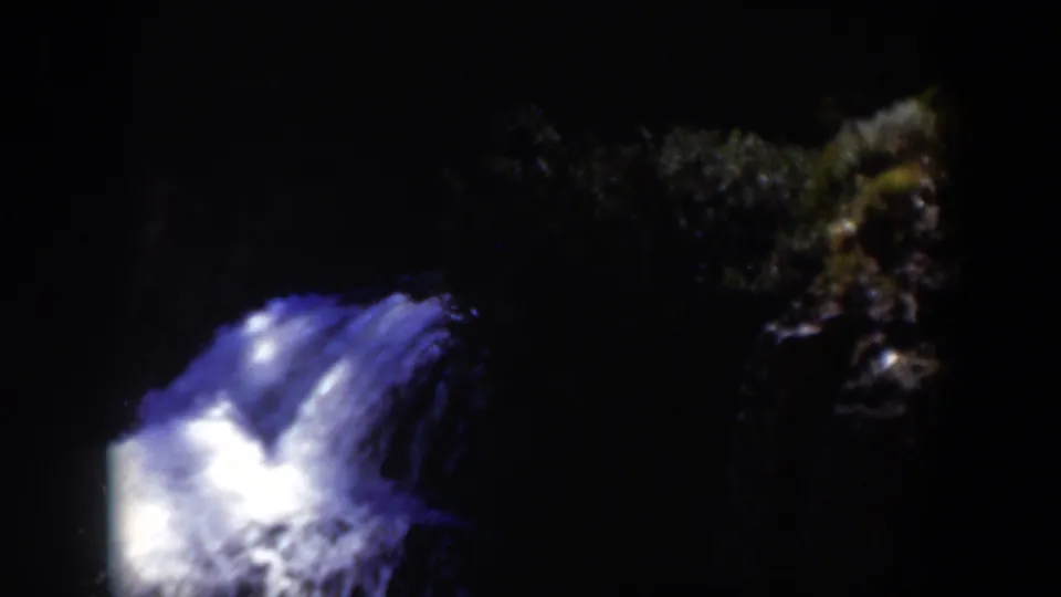1951 Wyoming 8mm frame showing the glowing cascade with a darker rocky bank and forest texture at the right.