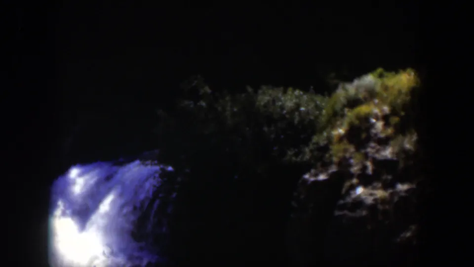 1951 Wyoming-associated 8mm frame showing a bright blue-white water current against near-black rocks and faint foliage.