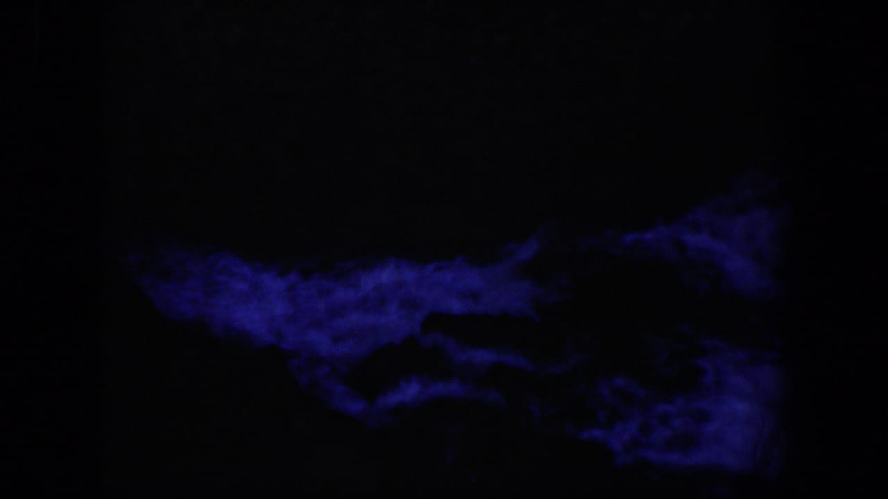 1951 Wyoming-associated 8mm frame showing a low band of deep blue current beneath a nearly black rock area.