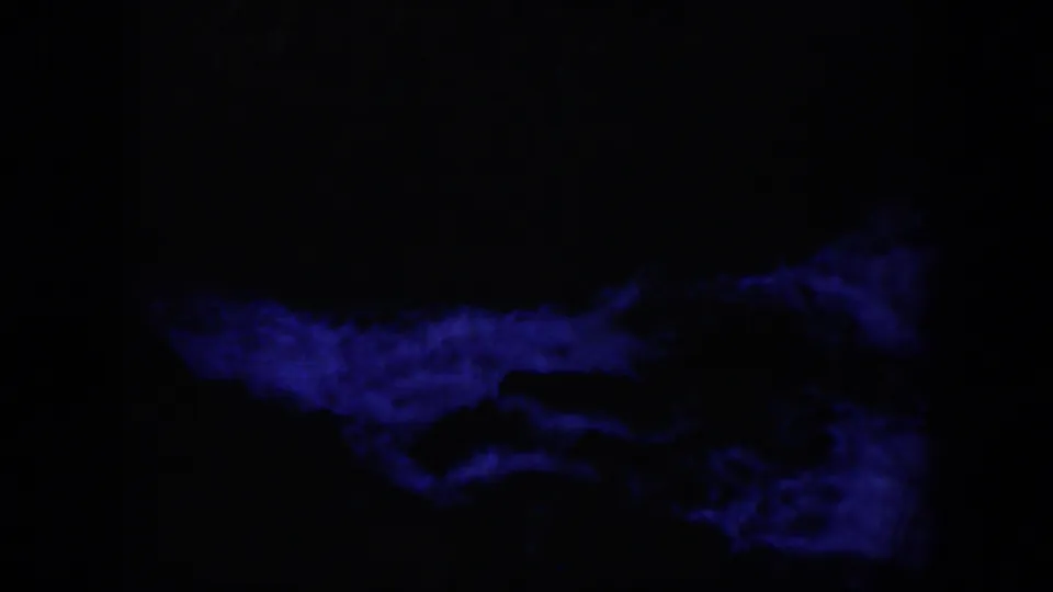 1951 Wyoming-associated 8mm frame showing a low band of deep blue current beneath a nearly black rock area.