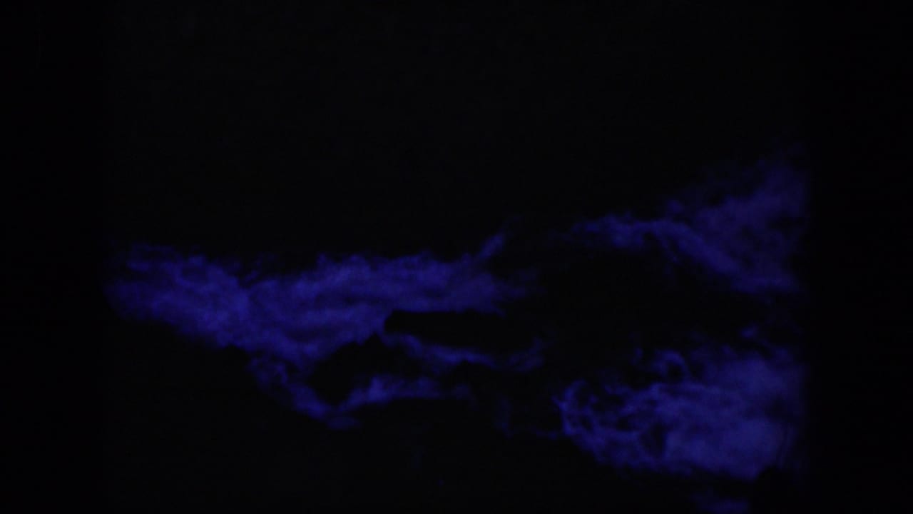 1951 Wyoming-associated 8mm frame with blue illuminated current moving below a large dark rock silhouette.