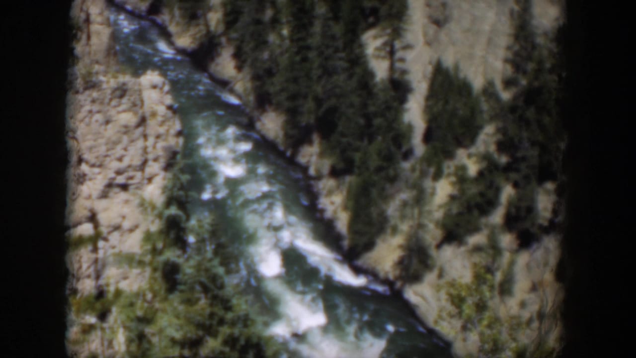 1951 Wyoming home-movie view of river rapids winding between pale rock faces and dark conifer growth.