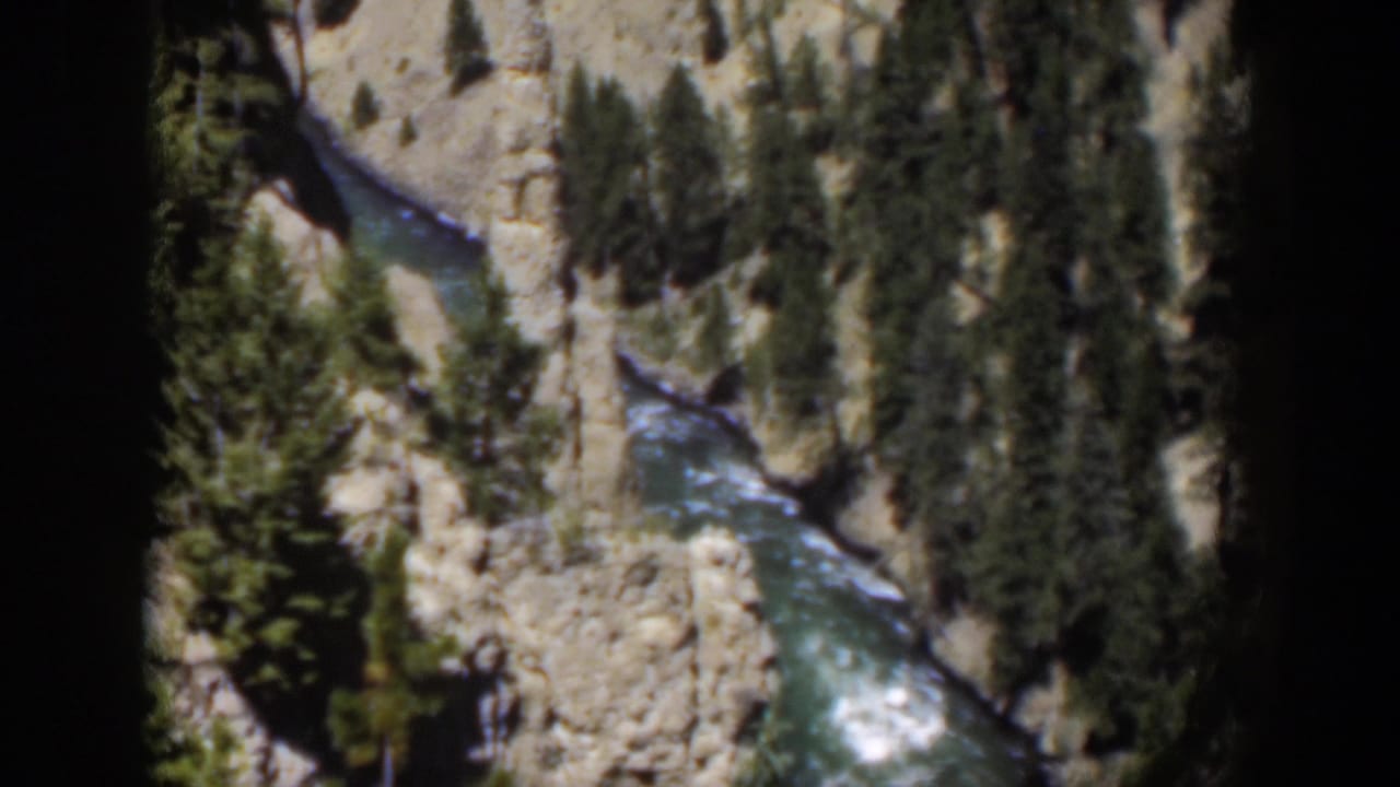 1951 Wyoming home-movie view of a blue-green river below pale canyon walls and clustered evergreens.