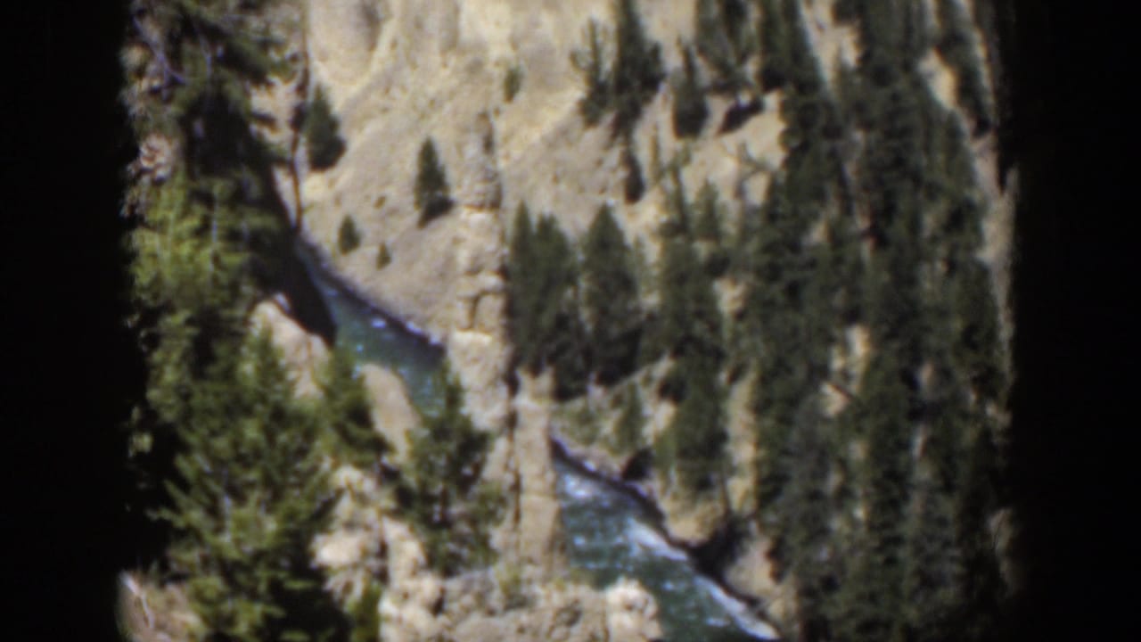 1951 Wyoming 8mm frame from a high overlook, with river water cutting through a tree-lined canyon.